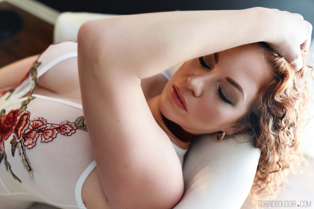 woman with red curly hair, eyes closed, laying back on chair